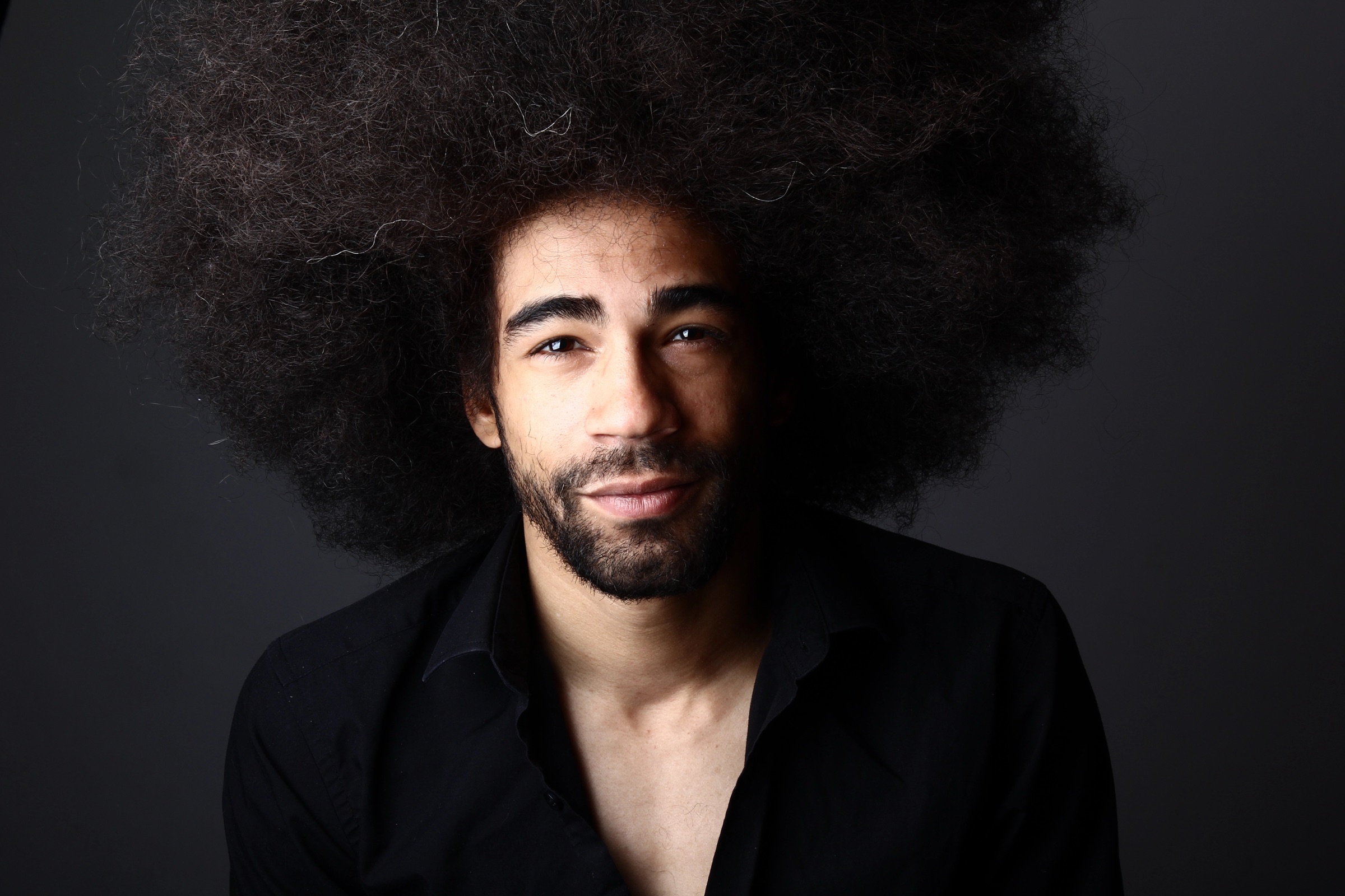 Portrait of a creator lit cleanly against a dark studio background